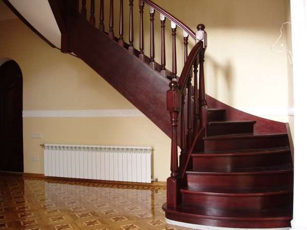 деревянная лестница с поворотом в интерьере гостиной