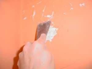 photo scraping water-damaged peeling paint and plaster from a wall
