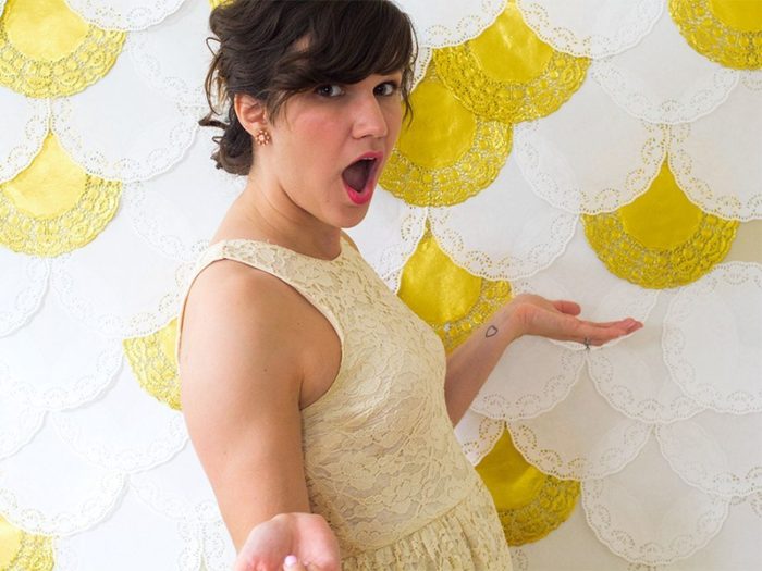 A woman creating a photography studio background with paper doilies