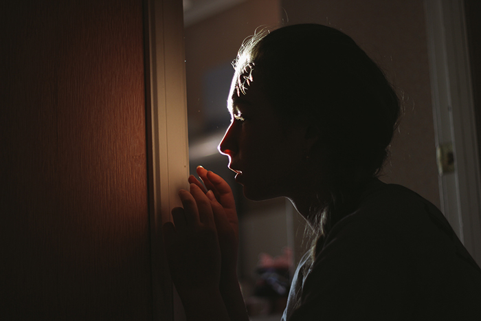 Atmospheric indoor portrait of a girl pushing her face against a window pane