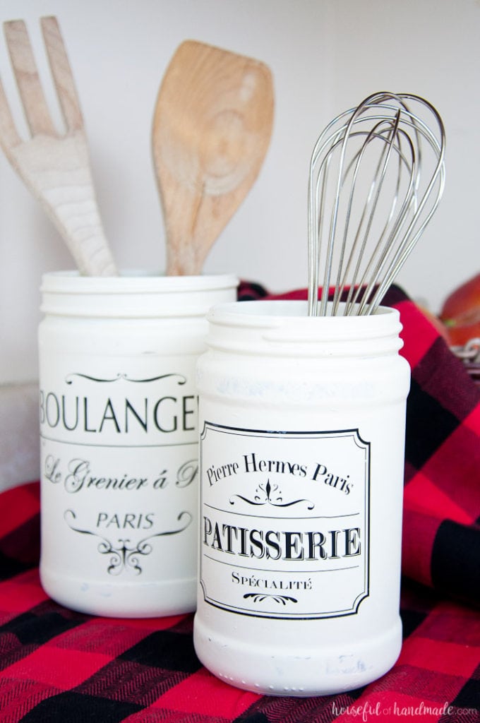 Two old jars refinished with white paint and french quotes shown as kitchen jars.
