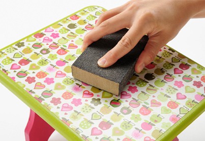 Sanding a decoupage stool with a sanding block