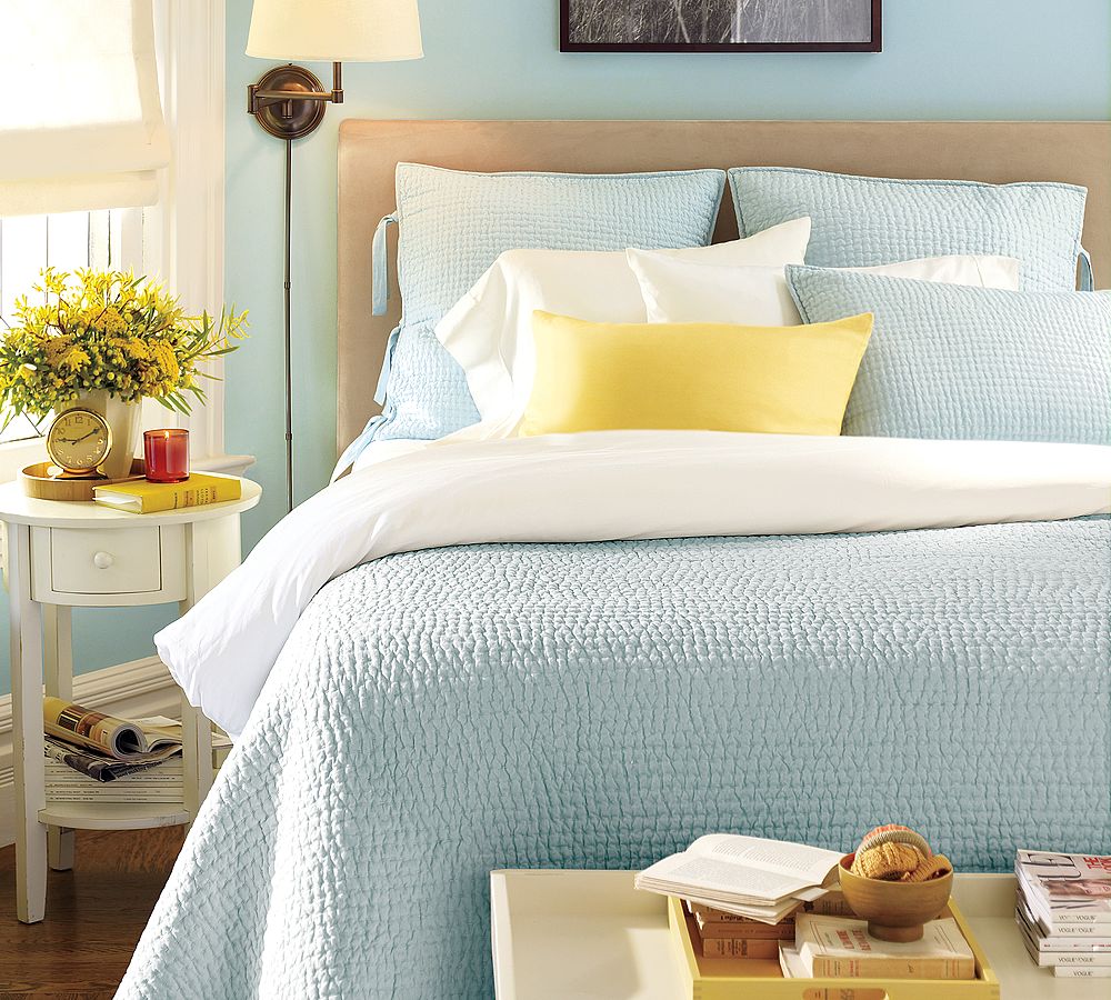 Голубое одеяло, подушки и стены в спальне