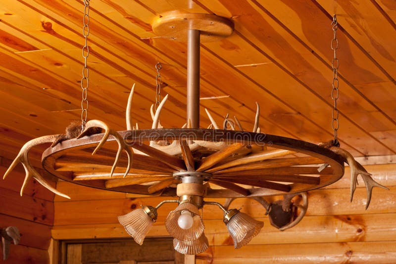 Antler Chandelier. With light fixture hanging from the wooden ceiling of a log cabin stock images