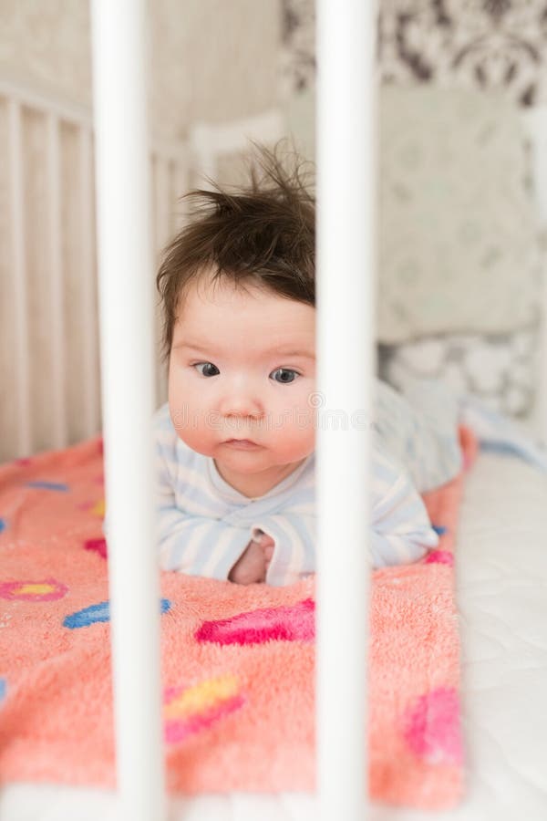 Baby in the crib. Funny baby in a white canopy bed. Children`s room interior and bedding for children. Laughing little boy playin royalty free stock photography