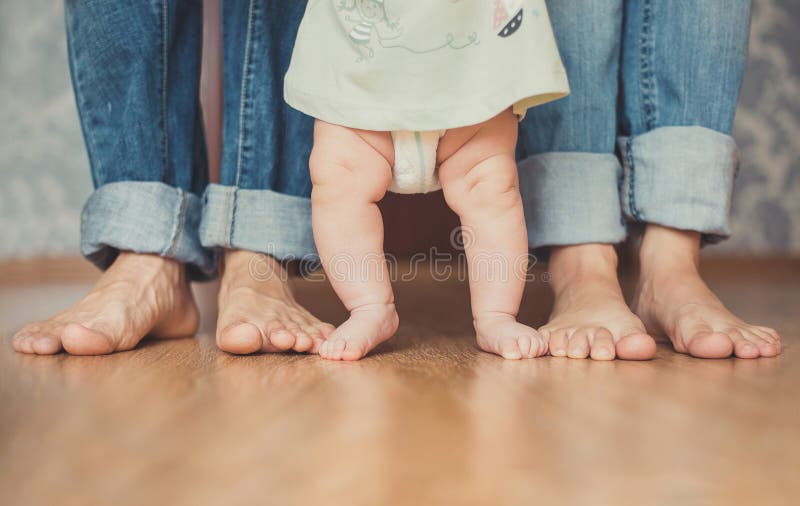 Closeup portrait of a mother teaching baby to walk indoors stock photography