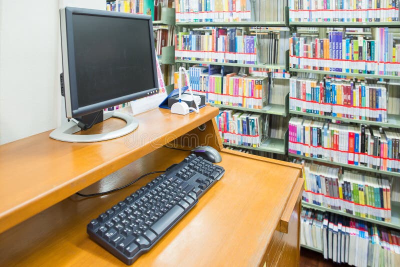computer in a library with many books and shelves in the background stock image