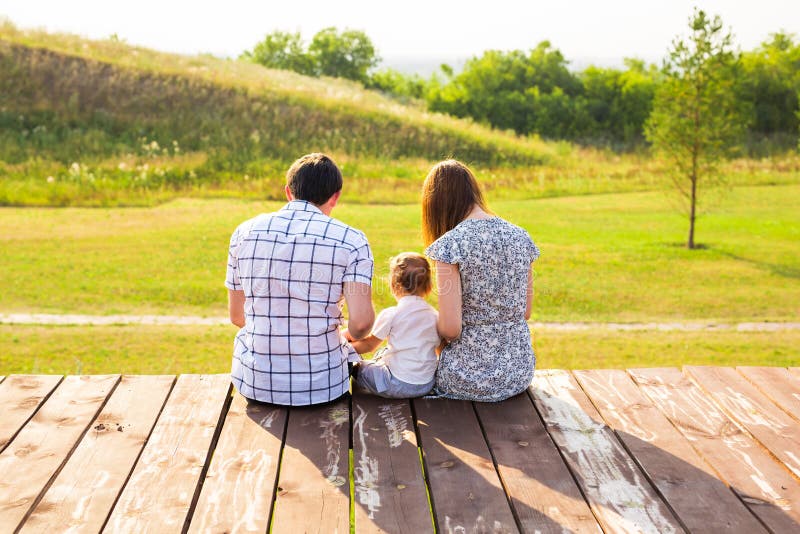 Family portrait. Picture of happy loving father, mother and their baby outdoors. Daddy, mom and child against green hill stock photos