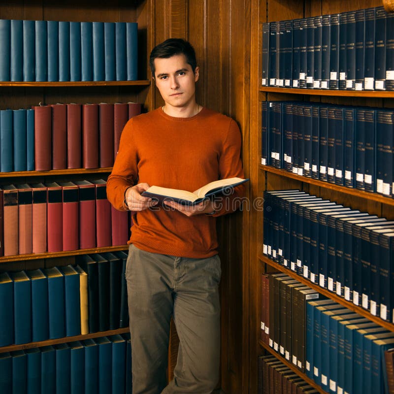 Man with a book standing in the vintage library shelves. stock images