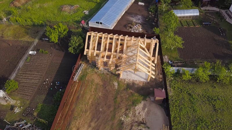 Plot with construction of wooden house. Clip. Top view on frame of wooden house on private country plot in summer. Frame. Of wooden house in process of royalty free stock photos