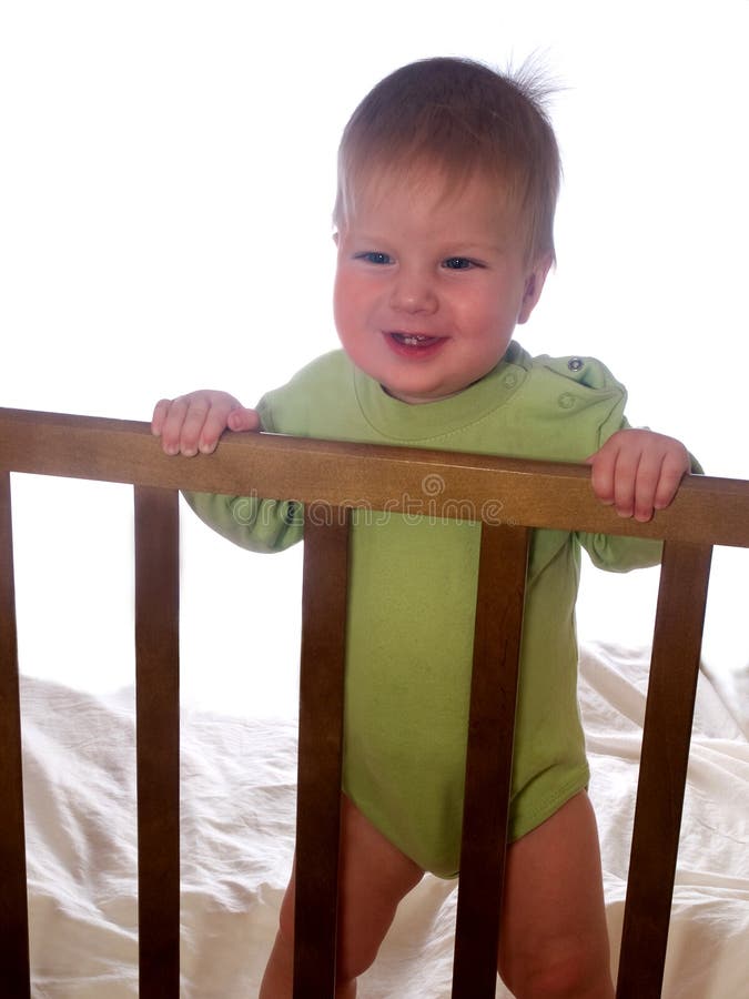 Smiling baby at the nursery room cot stock image