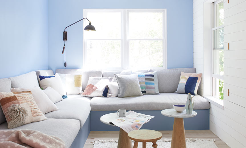 Light blue living room walls frame a large gray banquette