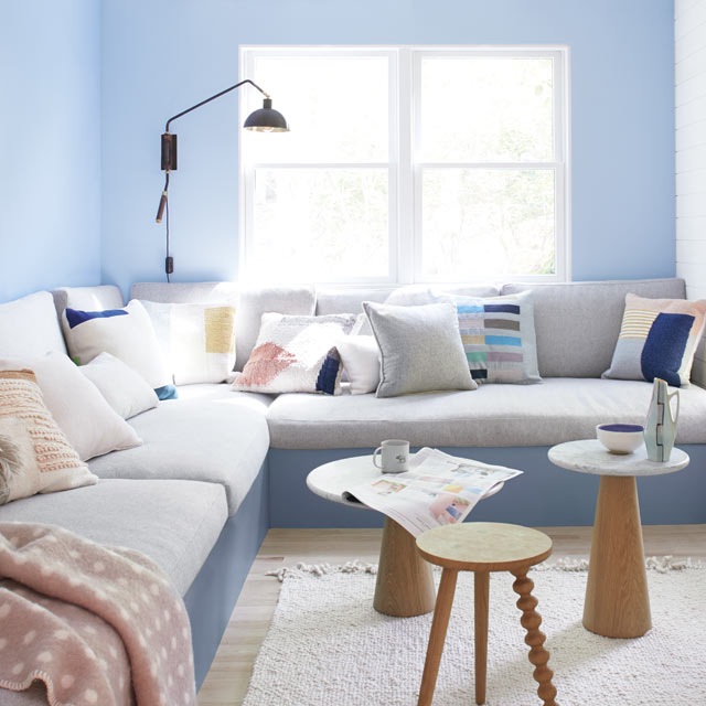 Light blue living room walls frame a large gray banquette Light blue living room walls frame a large gray banquette