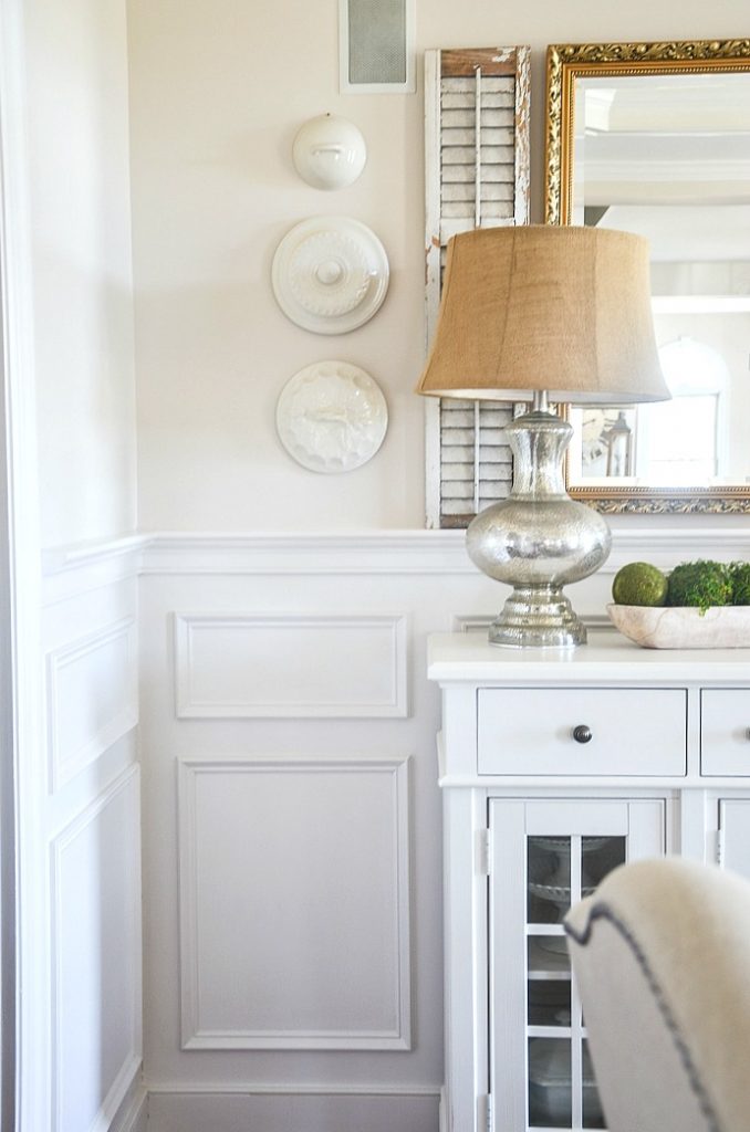 Neutral color wall with vintage lids hanging on it.